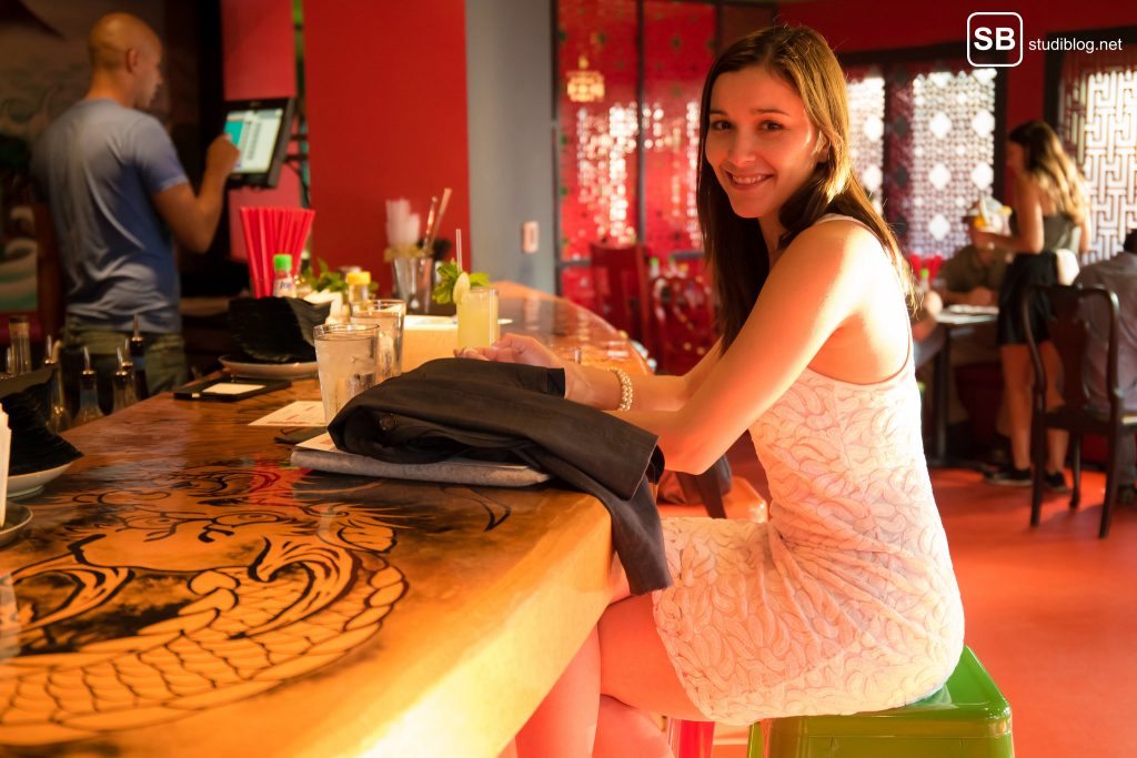 Katastrophen beim Date: Frau wartet im weißen Kleid am Tresen einer Bar.