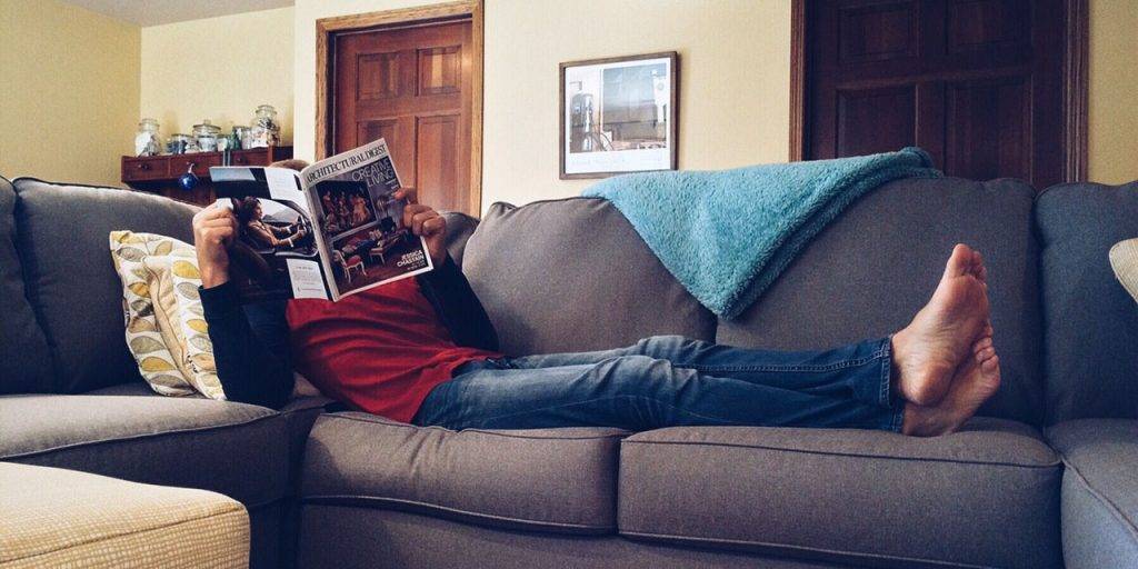 Selbstständig: Mann genießt seinen Feierabend bei einem Magazin auf der Couch 