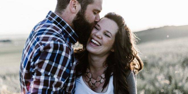Die große Liebe über online-Dating: Mann küsst lachende Frau auf die Wange