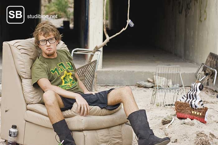Obdachloser Student sitzt auf einer Couch in einer Ruine zum Thema mehr Geld als Student